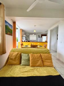 a bedroom with two beds with yellow sheets and a kitchen at Maison charmante avec jardin clos à Sainte-Anne in Sainte-Anne