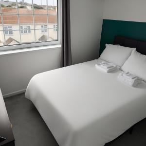 un letto bianco in una stanza con una finestra di Central Cornwall Home a Redruth