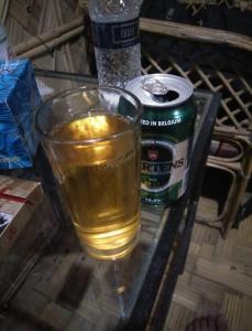 a glass of beer and a can on a table at Nishorgo Nirob Eco Resort in Sreemangal