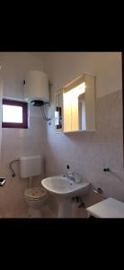 a bathroom with a sink and a toilet and a mirror at Apartman Perka in Valbandon