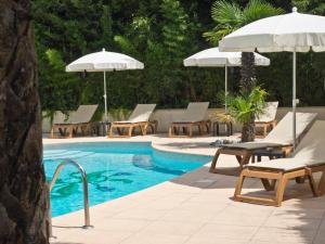 a swimming pool with lounge chairs and umbrellas at Hotel Les Oliviers in Fayence
