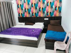 a bedroom with two beds and a chair in it at HOTEL RAMANAND PALACE UJJAIn in Ujjain +3 photos