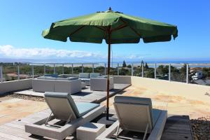 a patio with chairs and an umbrella on a roof at Lagoon Terrace Penthouse with sea view in Plettenberg Bay