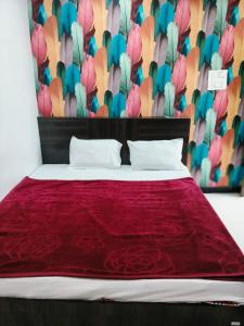 a bed with a red comforter and a wall with flowers at HOTEL RAMANAND PALACE UJJAIn in Ujjain