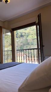 a bedroom with a bed and a large window at El Mirador de las Vegas in Potes