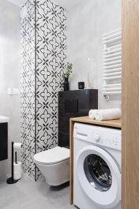 Un baño con inodoro y lavadora. en Stella Apartment, en Katowice