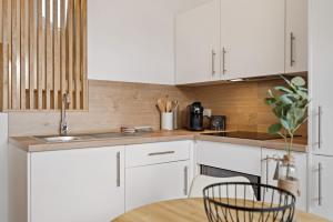 a kitchen with white cabinets and a wooden wall at Studio avec terrasse à 10min de Rouen in Déville-lès-Rouen