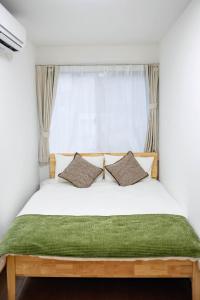 a bed with two pillows in front of a window at Osaka Purestay 5 rooms 2 parking spaces two balconies 8-11 人 Wi-Fi 玉出西 天下茶屋 心斎橋 道頓堀 近い 一 戸建 in Osaka