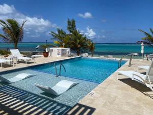 a swimming pool with chairs and the ocean in the background at The No Problem at Cottages in Sand Bluff
