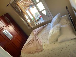 ein Schlafzimmer mit einem Bett mit Kissen und einem Fenster in der Unterkunft casa temporada pedra azul in Domingos Martins + 3 Fotos
