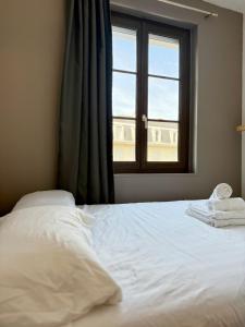 Un dormitorio con una cama blanca con una ventana. en Le Continental - Calme et Centre-Ville, en Aix-les-Bains