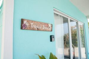 ein Schild an einer blauen Wand neben einem Fenster in der Unterkunft The Tropical Breeze Cottage in Sand Bluff