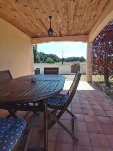 a wooden table and chairs on a patio at Gîtes Le Chemin du Romarin in Meursac