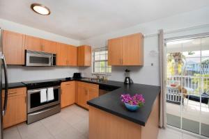 a kitchen with wooden cabinets and a black counter top at Snug Harbour View Condo #7 in George Town