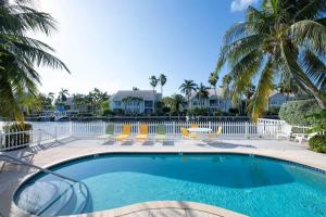a swimming pool with palm trees and houses at Snug Harbour View Condo #5 in George Town