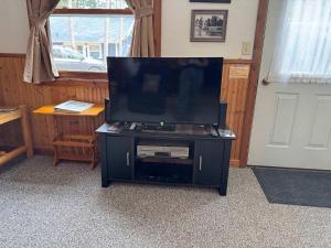TV de pantalla plana en un soporte negro en una habitación en Duxbury - Cozy Cottage on Lake Minocqua, en Minocqua