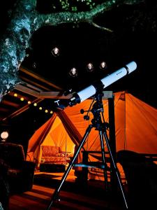 Un telescopio sobre un trípode delante de una tienda de campaña. en Family, en Štôla 2 fotos más