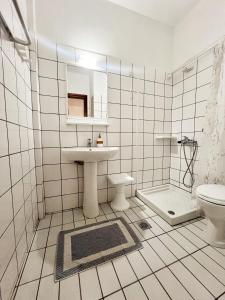 a white tiled bathroom with a sink and a toilet at Maria's Rooms in Skala Rachoniou +45 photos