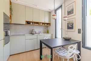 une cuisine avec une table noire et des armoires blanches dans l'établissement Raspail B - IDF - LB - Charming house at gates of Paris 3 people, à Bois-Colombes