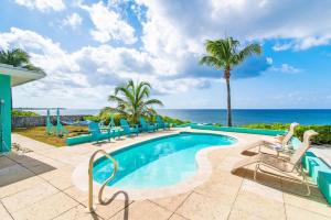 a pool with chairs and the ocean in the background at Blue Vista Villa 5BR Sleeps 16 in Old Man Bay
