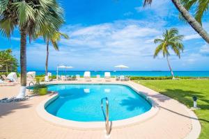 a swimming pool with palm trees and the ocean at Cocoplum #1 Condo in George Town