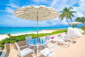 a table and chairs with an umbrella on the beach at Cocoplum #5 Condo in George Town
