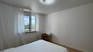 a white bedroom with a bed and a window at Затишне місце біля парку in Kyiv