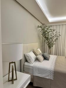 a white bedroom with a bed and a lamp at Refúgio Sofisticado Beira Mar in Florianópolis +21 photos