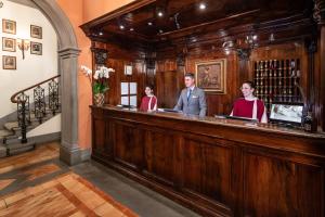 a man and two women standing behind a bar at Helvetia&Bristol Firenze – Starhotels Collezione in Florence