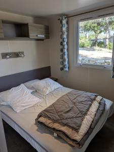an unmade bed in a bedroom with a window at Mobil-home dans les Gorges du Verdon in Moissac-Bellevue