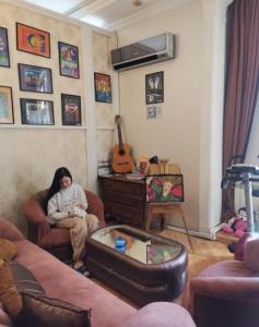 a woman sitting in a living room with a guitar at nizami m hostel in Baku