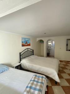 a bedroom with two beds and a checkered floor at Au soleil couchant in Mirleft