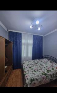 1 dormitorio con 1 cama y cortinas azules en nizami m hostel, en Baku