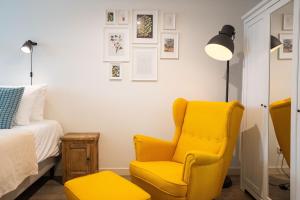 een slaapkamer met een gele stoel en een bed bij Nassau Canal Suites - in the heart of the city in Amsterdam