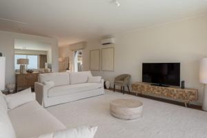 ein Wohnzimmer mit weißen Möbeln und einem Flachbild-TV in der Unterkunft Vila Venusta Tranquility and Views in Calheta in Calheta