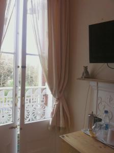 a window with a curtain and a door with a balcony at Trelawney Guest House in Falmouth