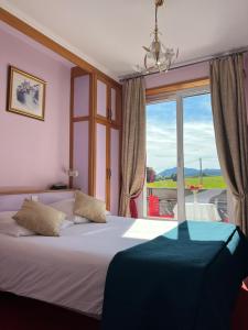 a bedroom with a bed and a large window at Hôtel l'Orée des Roches in Saales
