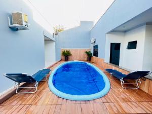 a large swimming pool on a wooden deck with chairs at Casa 19 pessoas, piscina e jacuzzi in Nova Mutum