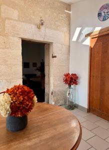 a room with a table with a vase of flowers on it at Gîte Le Patio Bleu in Saint-Romain +13 photos
