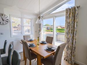 a dining room with a table and chairs and a clock at Cedar 1 in Lyme Regis