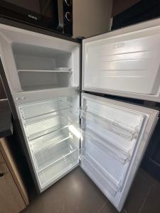 an empty refrigerator with its door open in a kitchen at L’Escale du lac in Brêmes