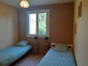 a bedroom with two beds and a window at Le gîte de l'Ecureuil - 4 personnes in Donges