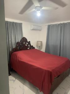 a bedroom with a bed with a red bedspread at res Montesino in San Felipe de Puerto Plata