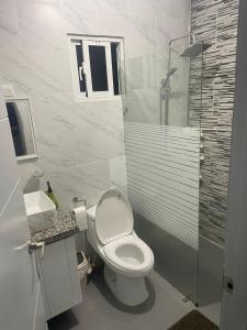 a white bathroom with a toilet and a shower at res Montesino in San Felipe de Puerto Plata