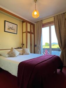 a bedroom with a bed and a large window at Hôtel l'Orée des Roches in Saales