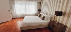 una camera da letto con un letto con lenzuola e cuscini bianchi di La Maison Piaf a Esposende