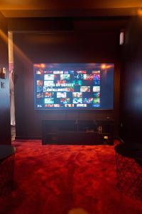 a large television screen in a room with a red carpet at Romance House in Arnouville-lès-Gonesse