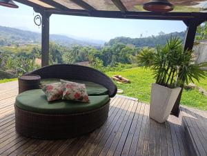 a wicker chair with two pillows on a wooden deck at casa para Oktoberfest in Blumenau
