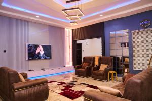 a waiting room with chairs and a flat screen tv at Ay crib 