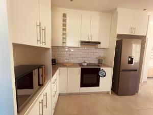a kitchen with white cabinets and a refrigerator at Biz & Bliss Work & Serene Views in Windhoek
